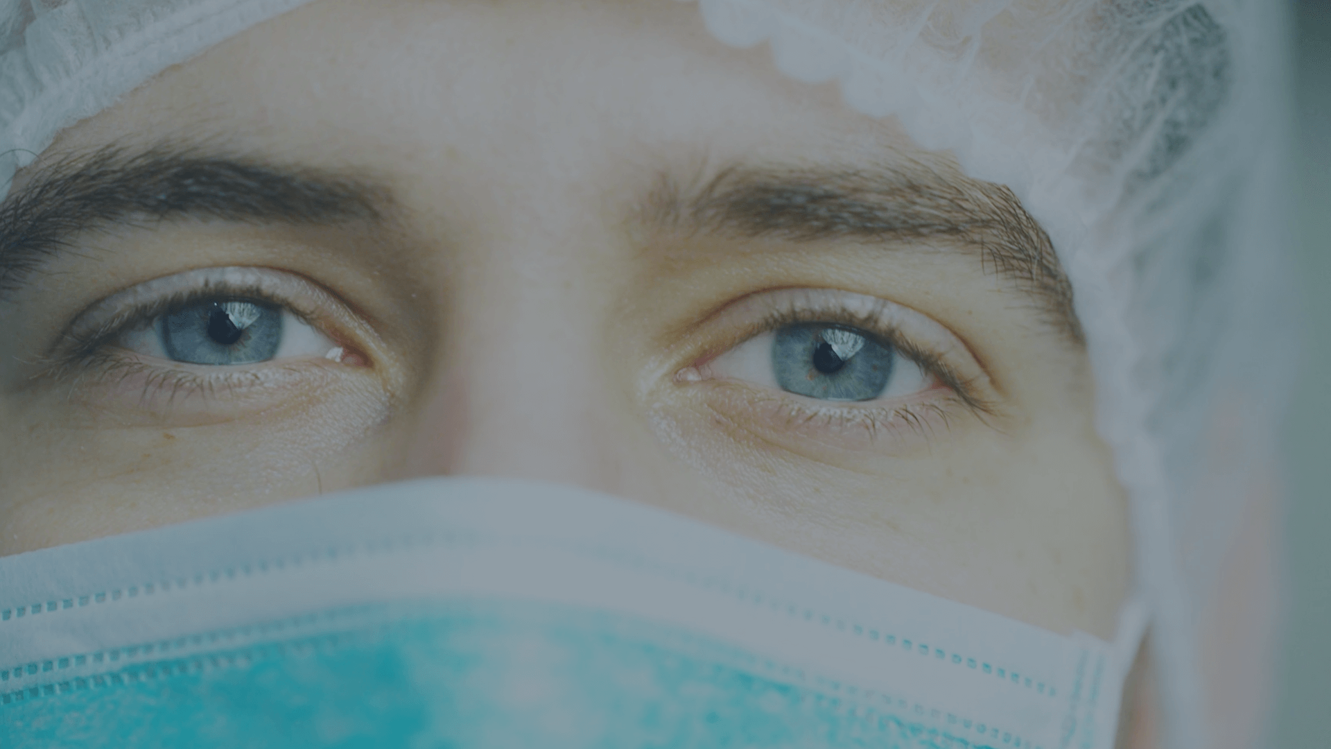 A doctor in a mask looks straight ahead